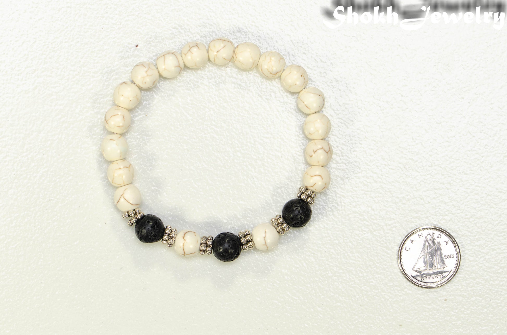 White Howlite and Black Lava Stone Bracelet beside a dime.