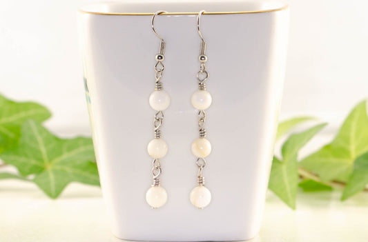 6mm White Natural Seashell Earrings displayed on a tea cup.