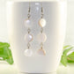 Long White Natural Seashell Earrings displayed on a coffee mug.