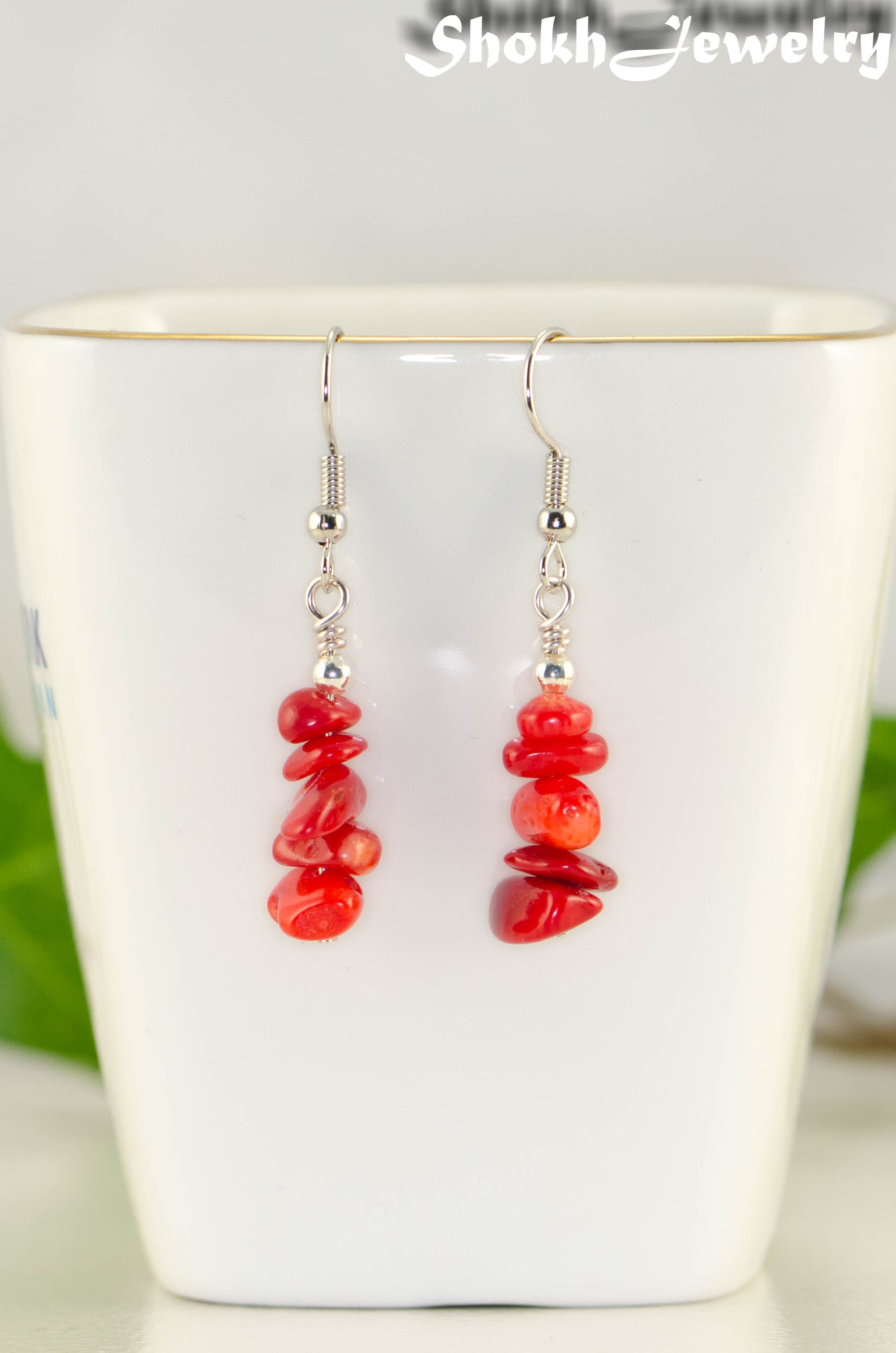 Simple Red Coral Chip Earrings displayed on a tea cup.