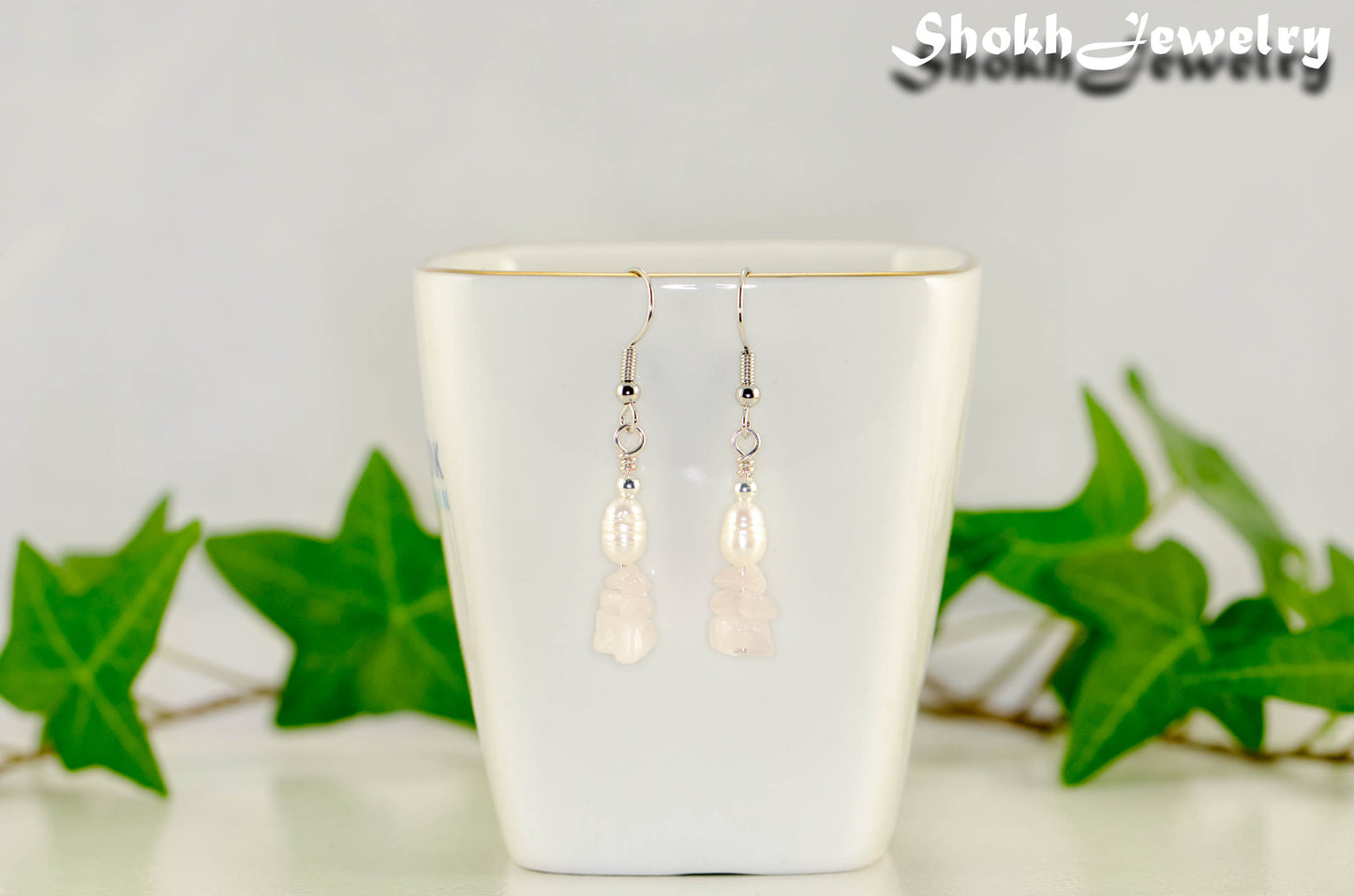 Natural Rose Quartz Chip and Pearl Earrings displayed on a tea cup