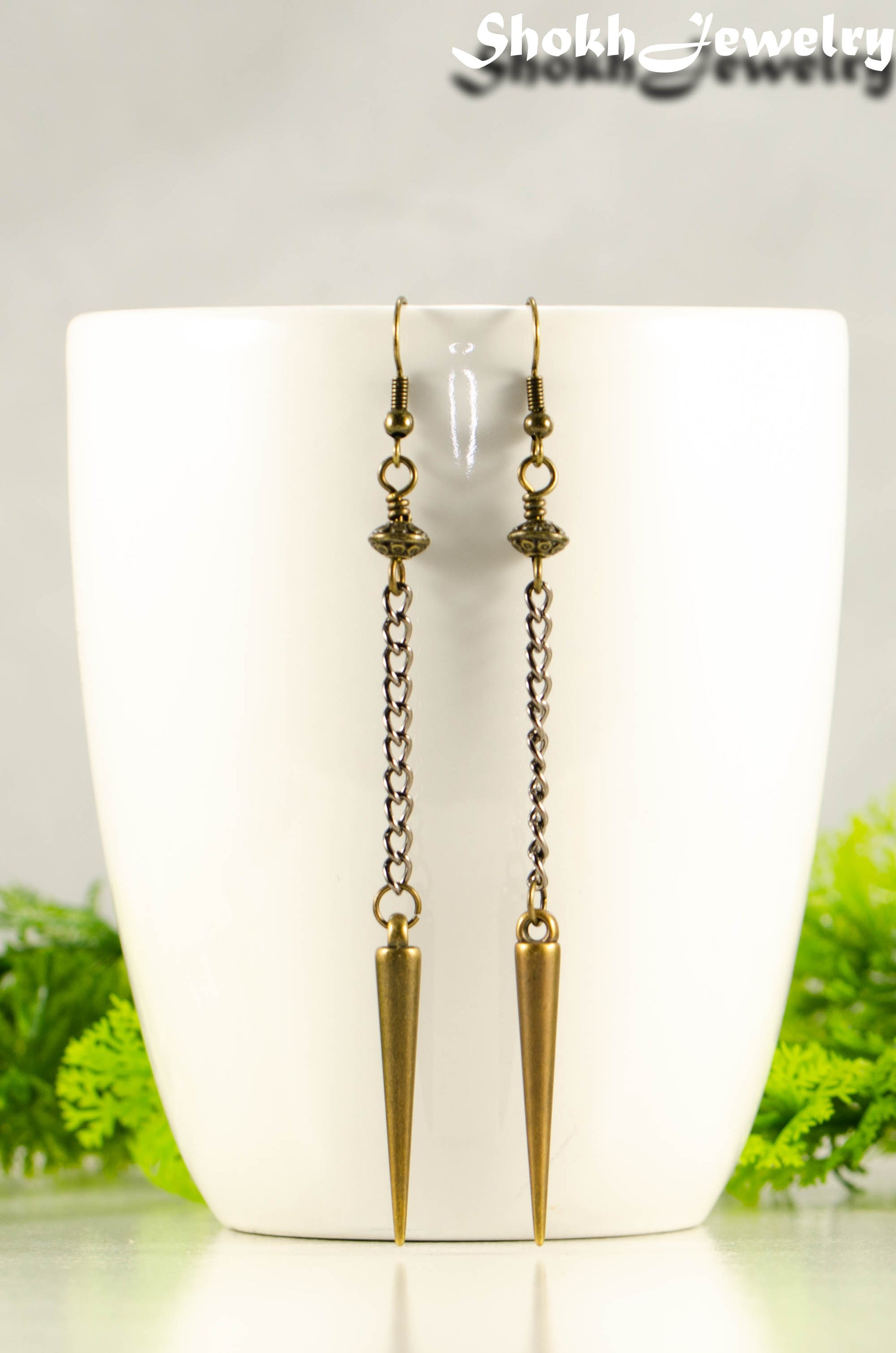 Statement chain and antique bronze spike earrings on a mug