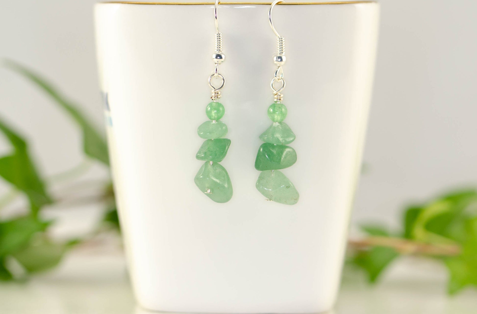 Simple Green Aventurine Crystal Chip Earrings displayed on a tea cup.