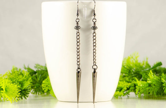 Statement chain and antique silver spike earrings on a coffee mug