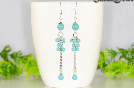 Long Stainless Steel Chain and Turquoise Howlite Earrings displayed on a coffee mug.