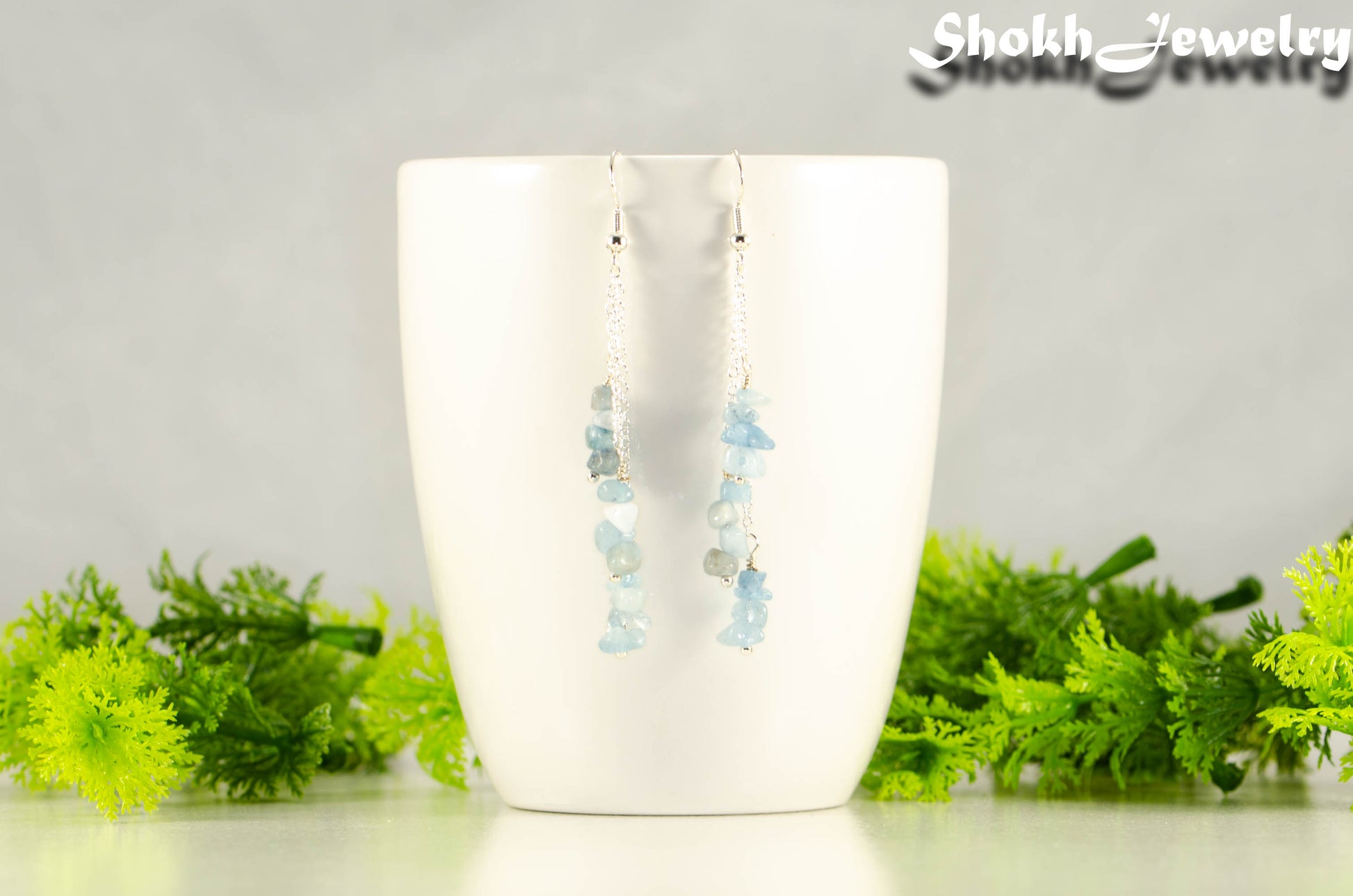 Long Silver Plated Chain and Aquamarine Crystal Chip Earrings on a mug