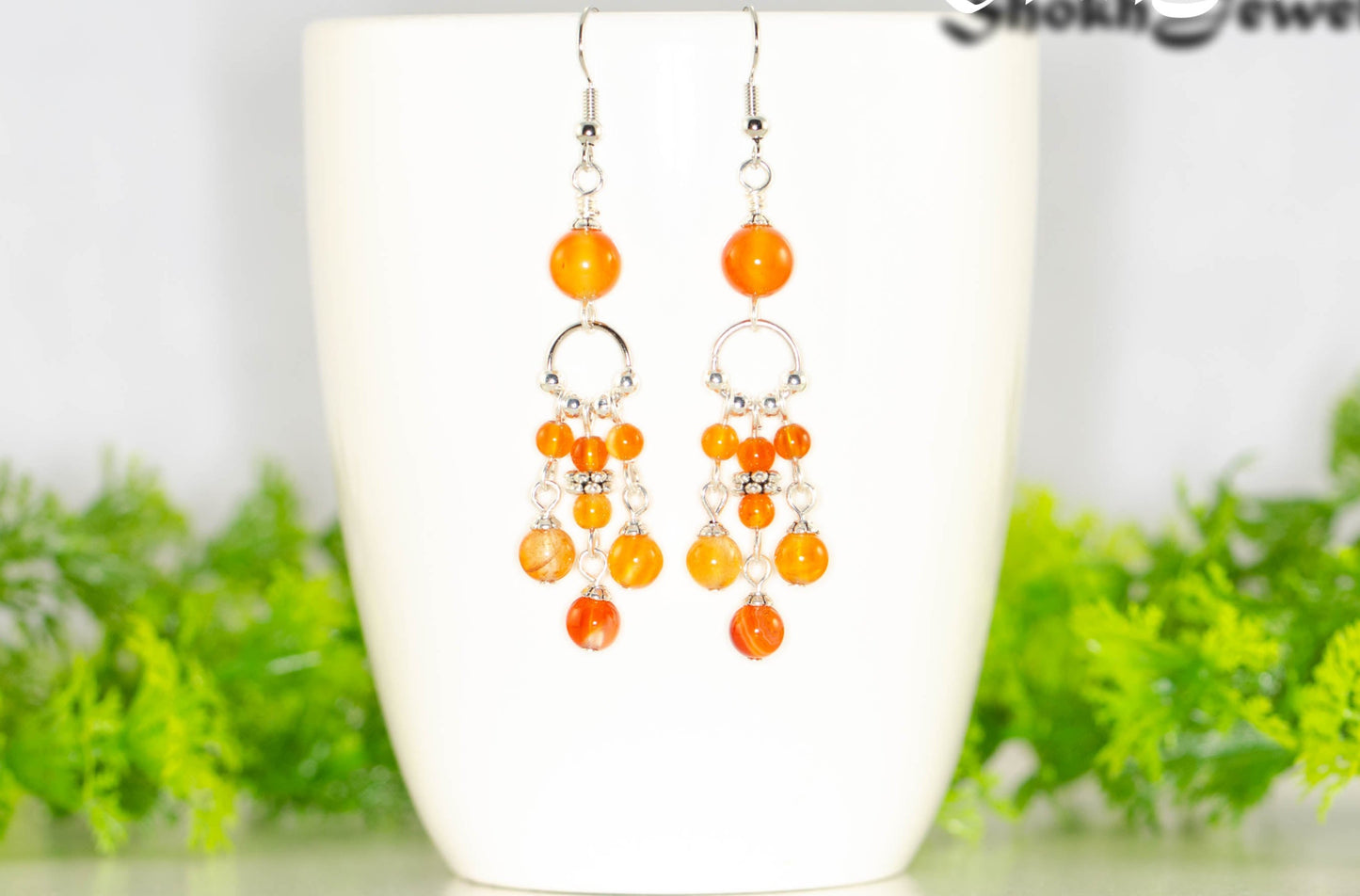 Statement Carnelian Crystal Chandelier Earrings displayed on a coffee mug.