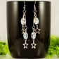 Clear Glass and Stainless Steel Star Earrings displayed on a black coffee mug.