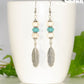 Statement White And Turquoise Howlite And Feather Earrings displayed on a coffee mug.