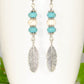 Close up of Statement Turquoise And White Howlite And Feather Earrings.