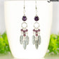 Statement Amethyst Crystal And Feather Earrings displayed on a coffee mug.