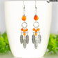 Statement Carnelian Crystal And Feather Earrings displayed on a coffee mug.