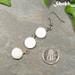 Long White Natural Seashell Earrings beside a dime.