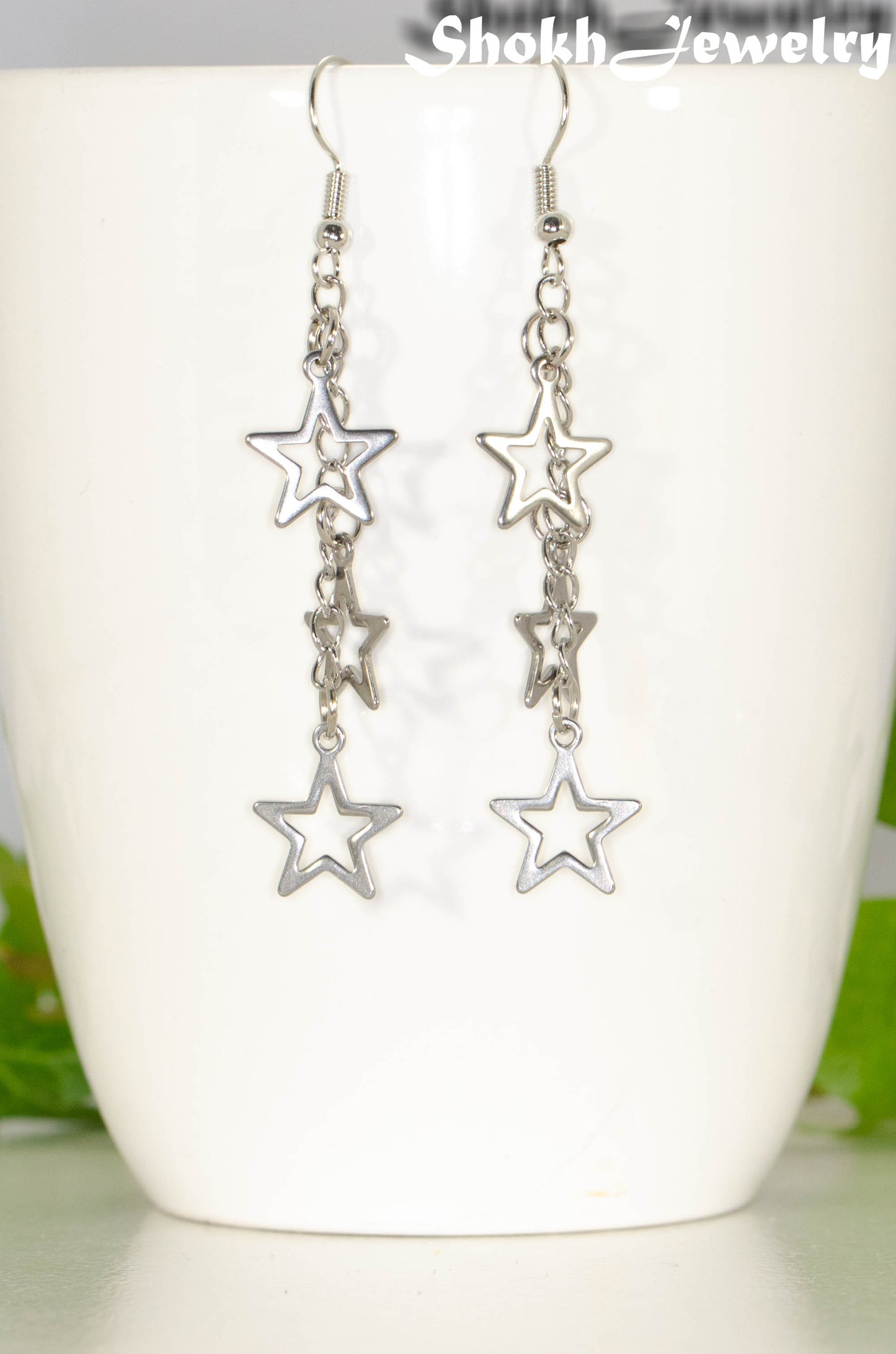 Stainless steel chain and star earrings on a mug