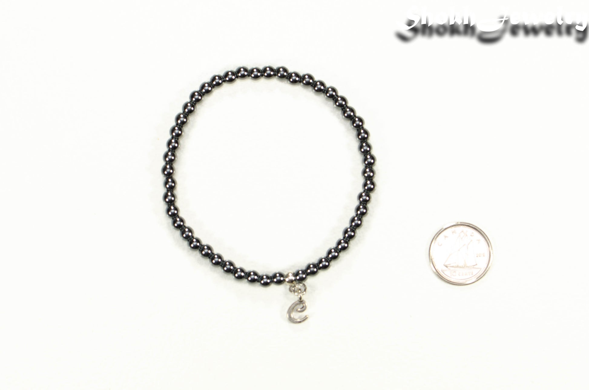 4mm Hematite Bracelet with Initial beside a dime