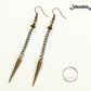 Statement chain and antique bronze spike earrings beside a dime