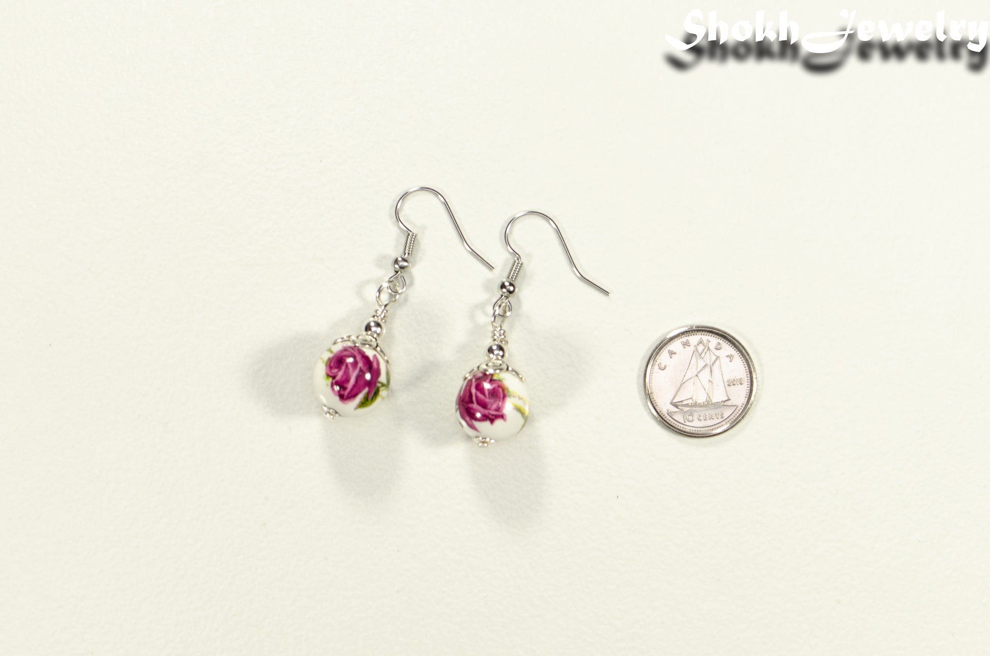 12mm Ceramic Pink Flower Earrings beside a dime.