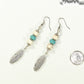 Statement White And Turquoise Howlite And Feather Earrings beside a dime.