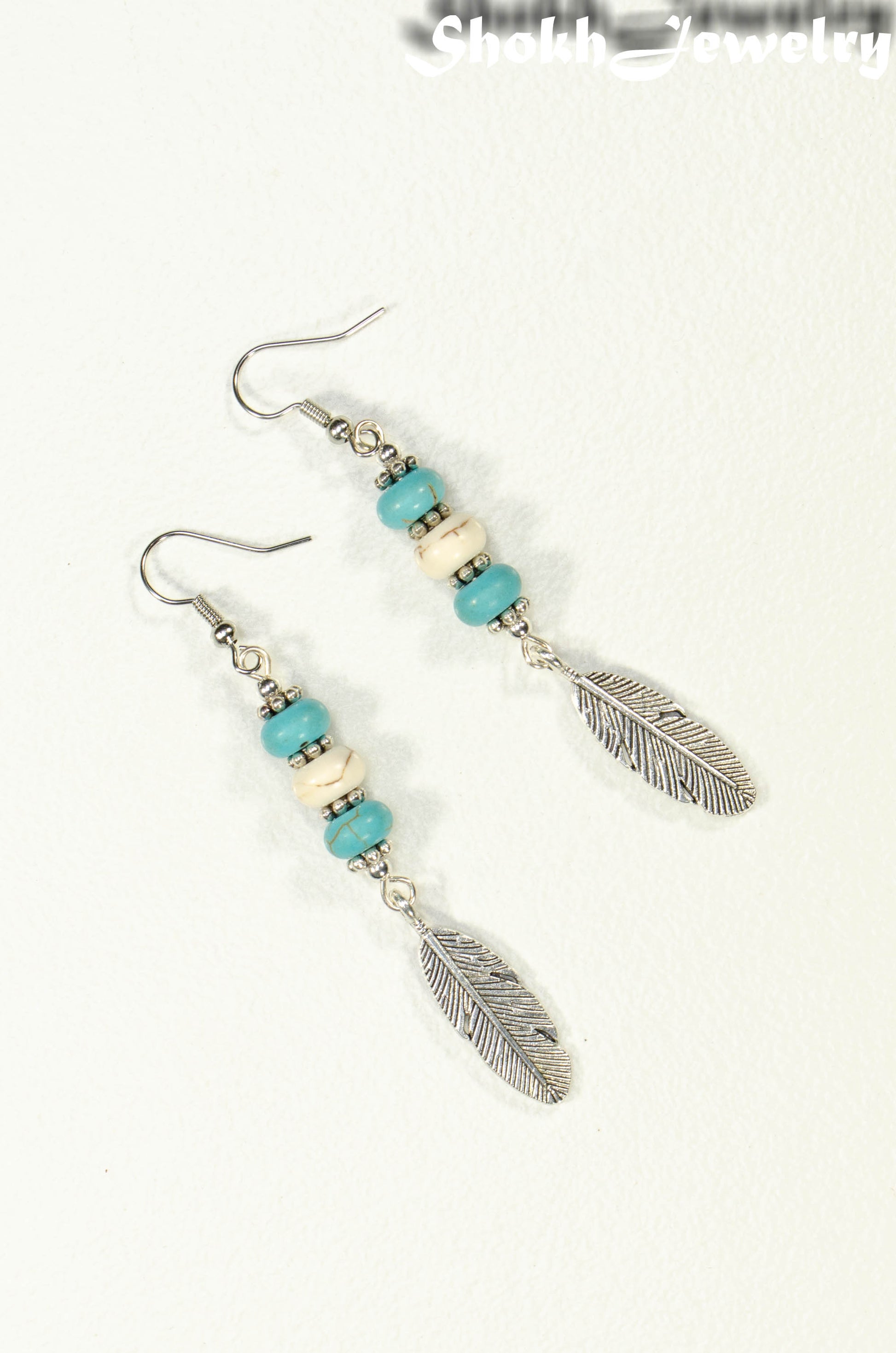 Top view of Statement Turquoise And White Howlite And Feather Earrings.