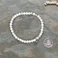 4mm White Howlite Bracelet with Initial beside a dime.