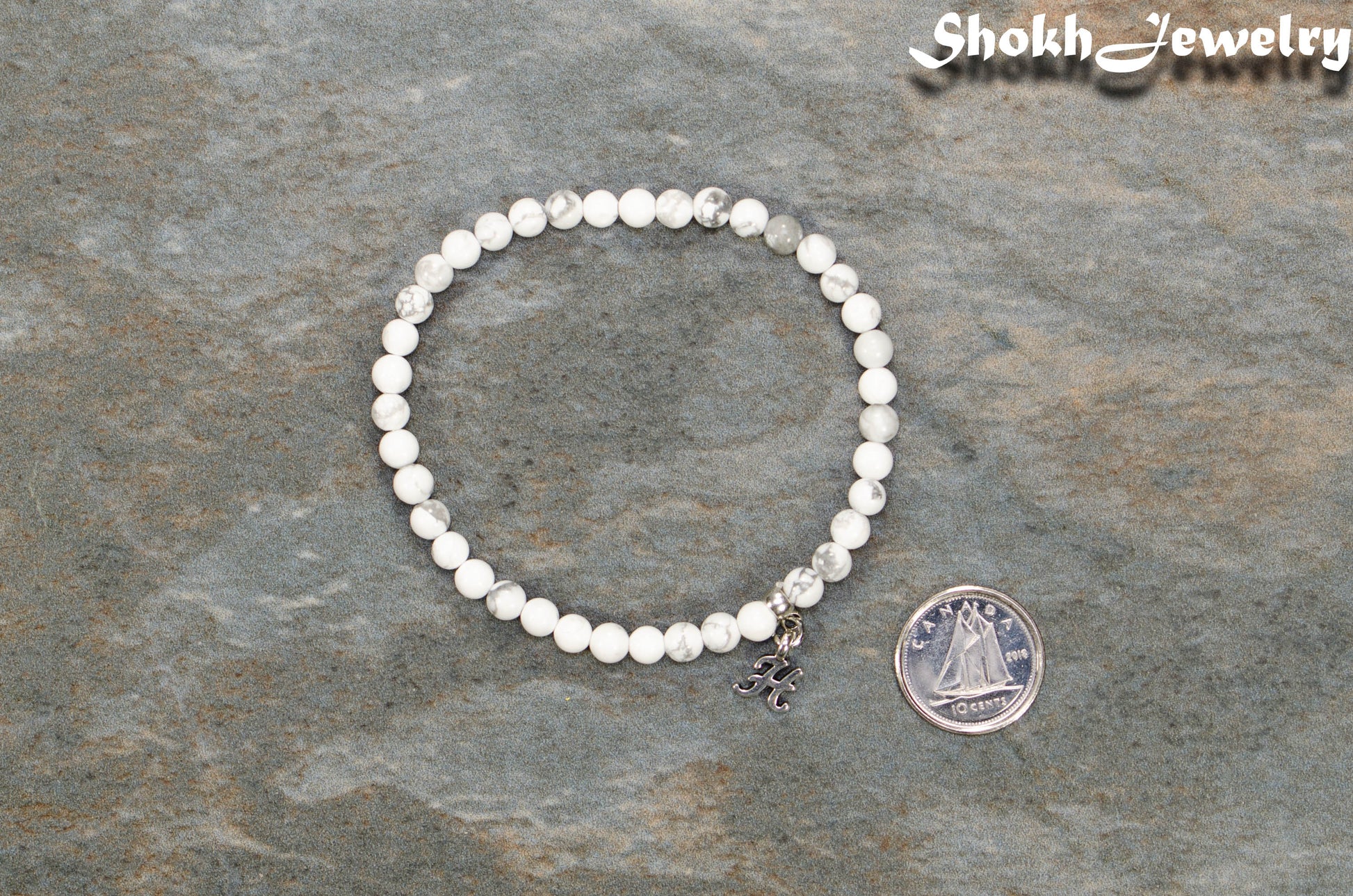 4mm White Howlite Bracelet with Initial beside a dime.