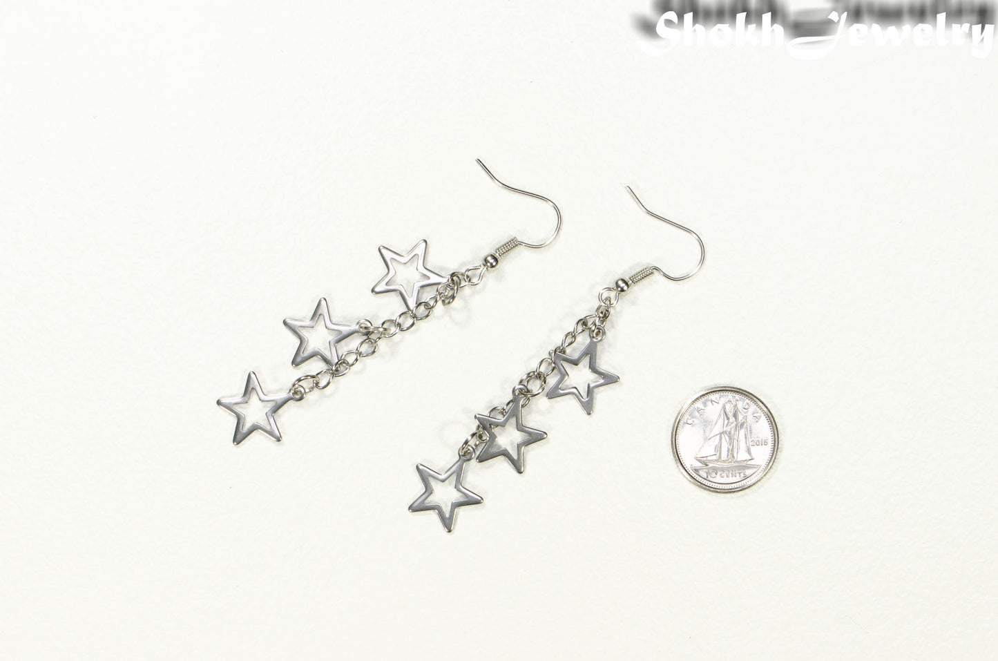 Stainless steel chain and star earrings beside a dime