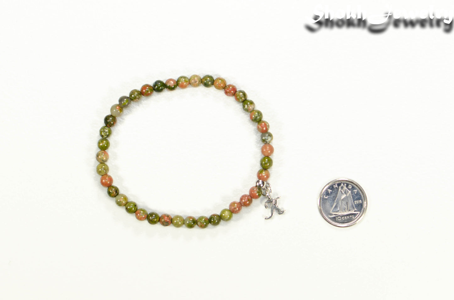 4mm Unakite Bracelet with Initial beside a dime.