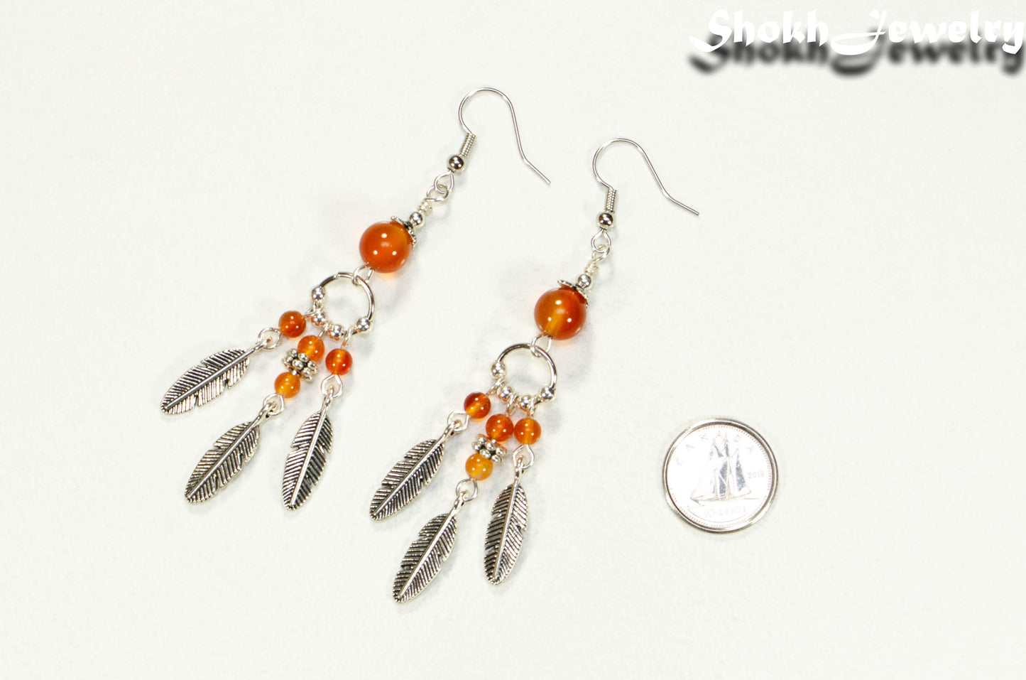 Statement Carnelian Crystal And Feather Earrings beside a dime.