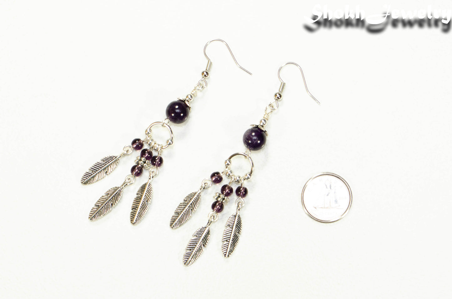 Statement Amethyst Crystal And Feather Earrings beside a dime.