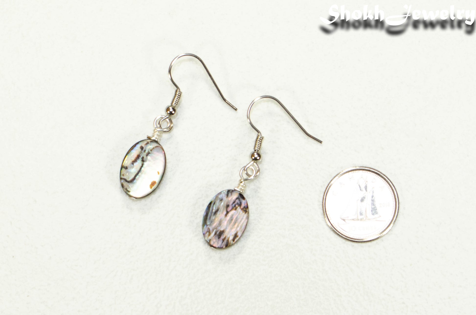 Simple Oval Abalone Shell Earrings beside a dime.