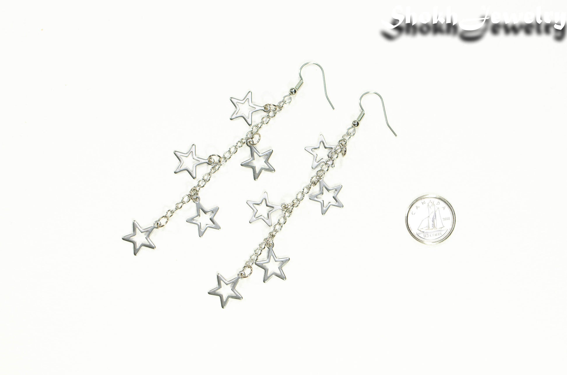 Long stainless steel chain and star earrings beside a dime