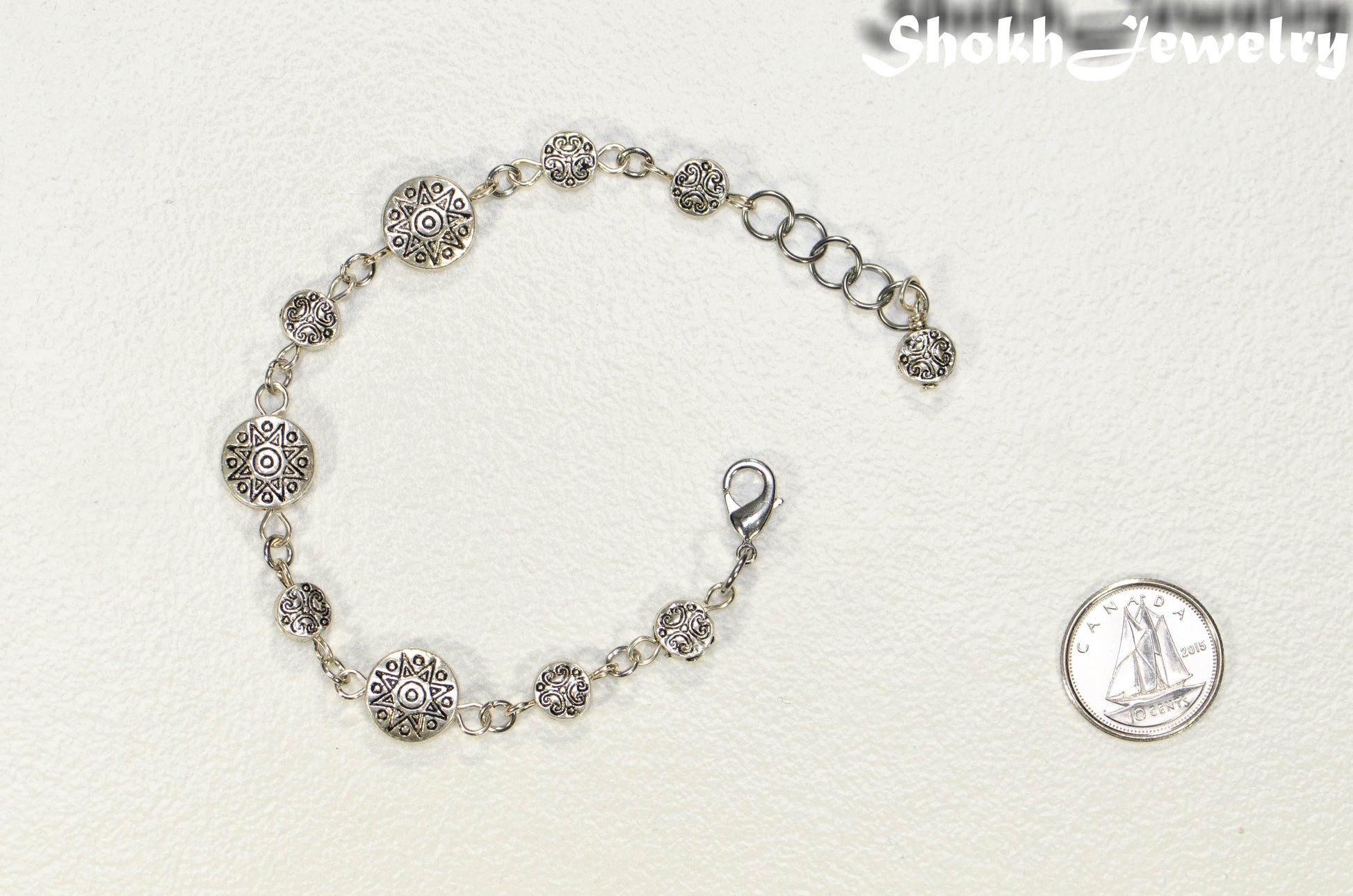 Tibetan Silver Sun and Moon Bracelet  beside a dime.