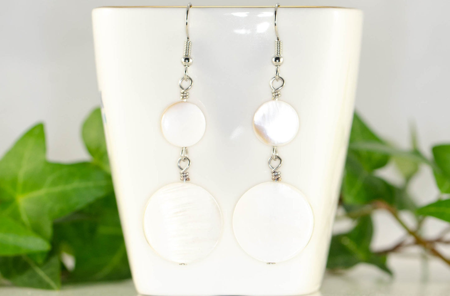Statement White Seashell Earrings displayed on a tea cup.