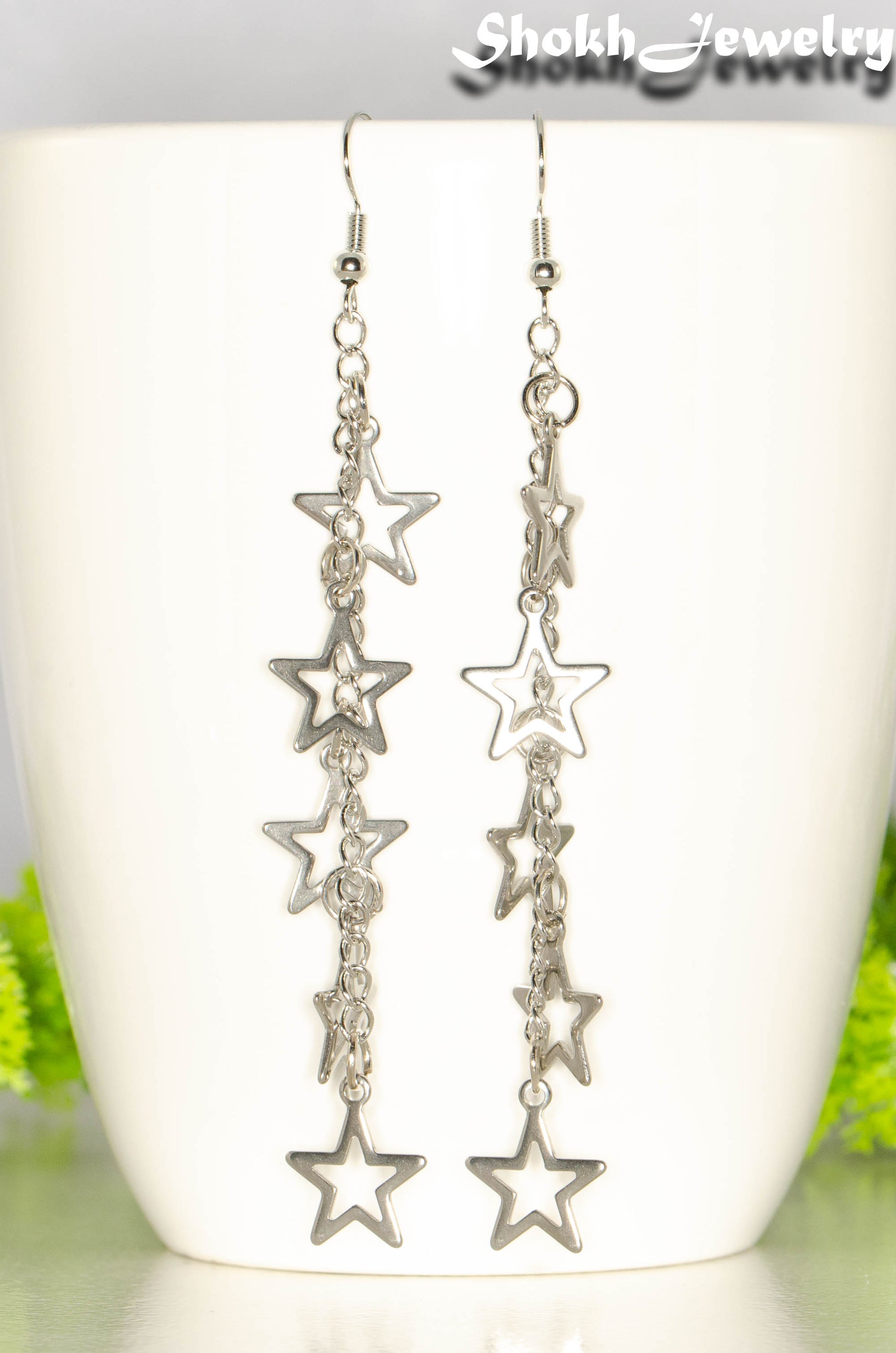 Long stainless steel chain and star earrings on a coffee mug