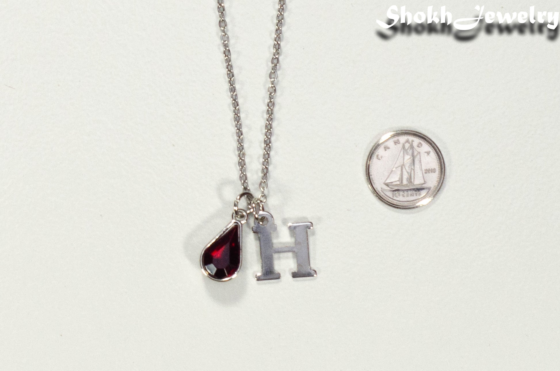 Personalized January Birthstone pendant beside a dime