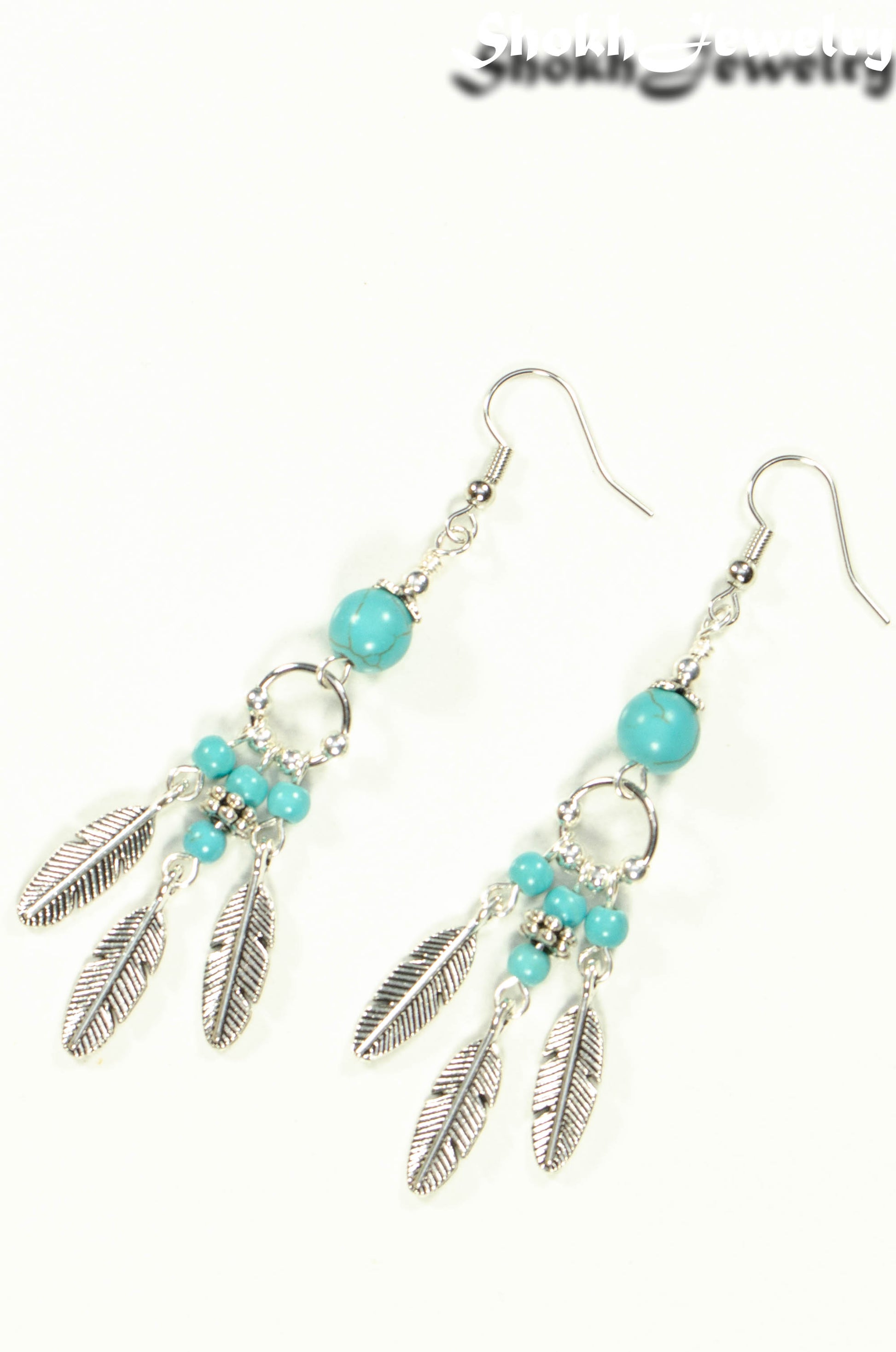 Top view of Statement Turquoise Howlite And Feather Earrings.