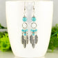 Statement Turquoise Howlite And Feather Earrings displayed on a coffee mug.