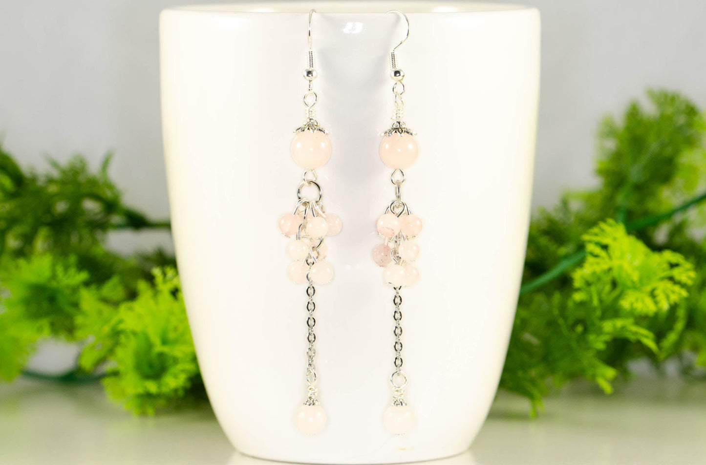 Long Stainless Steel Chain and Rose Quartz Earrings displayed on a coffee mug.